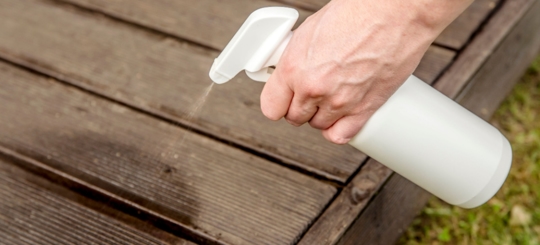 A person using a spraying tool on a wood object