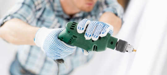 A person using a drilling machine on the wall